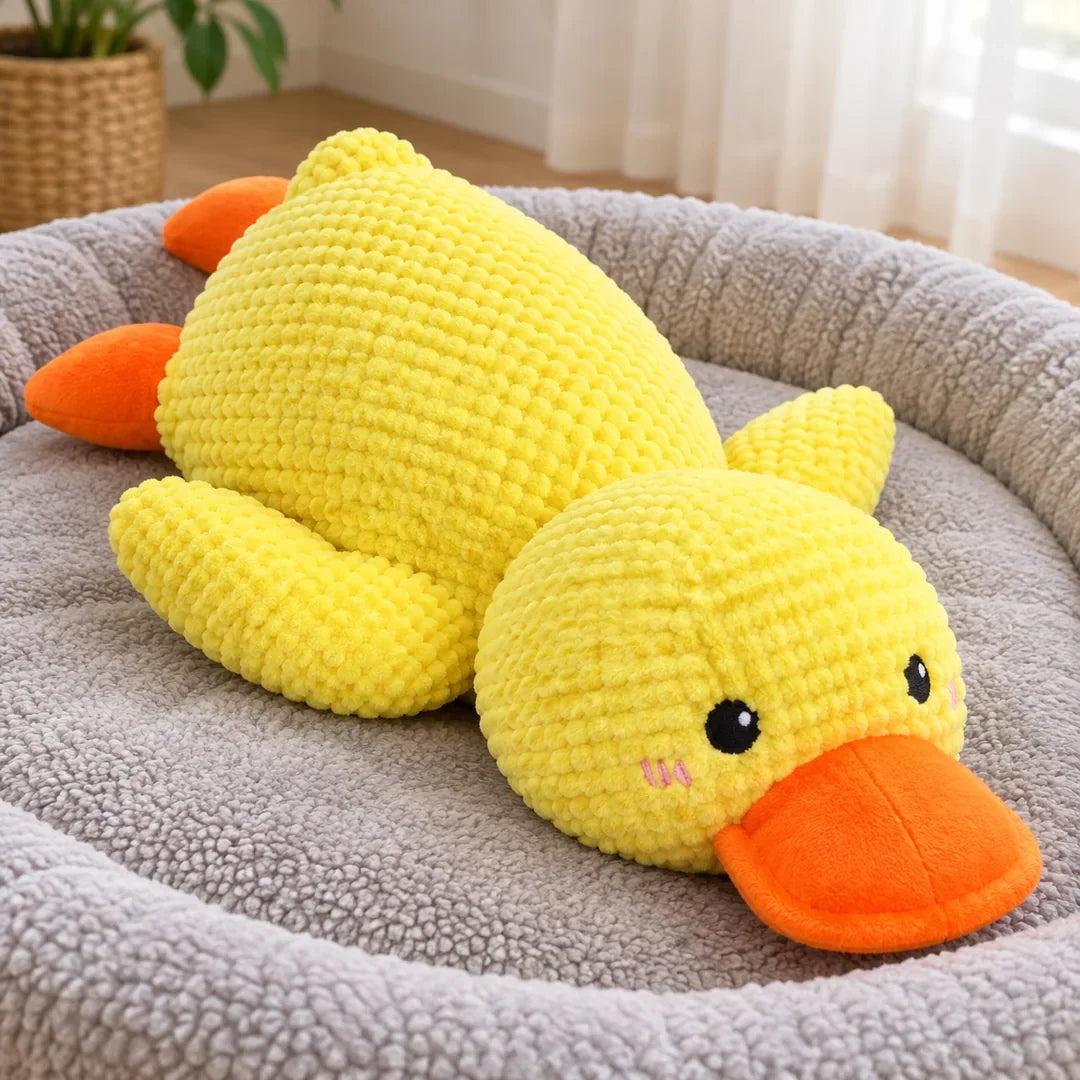 Pato de peluche amarillo para perro sobre una cama de perro