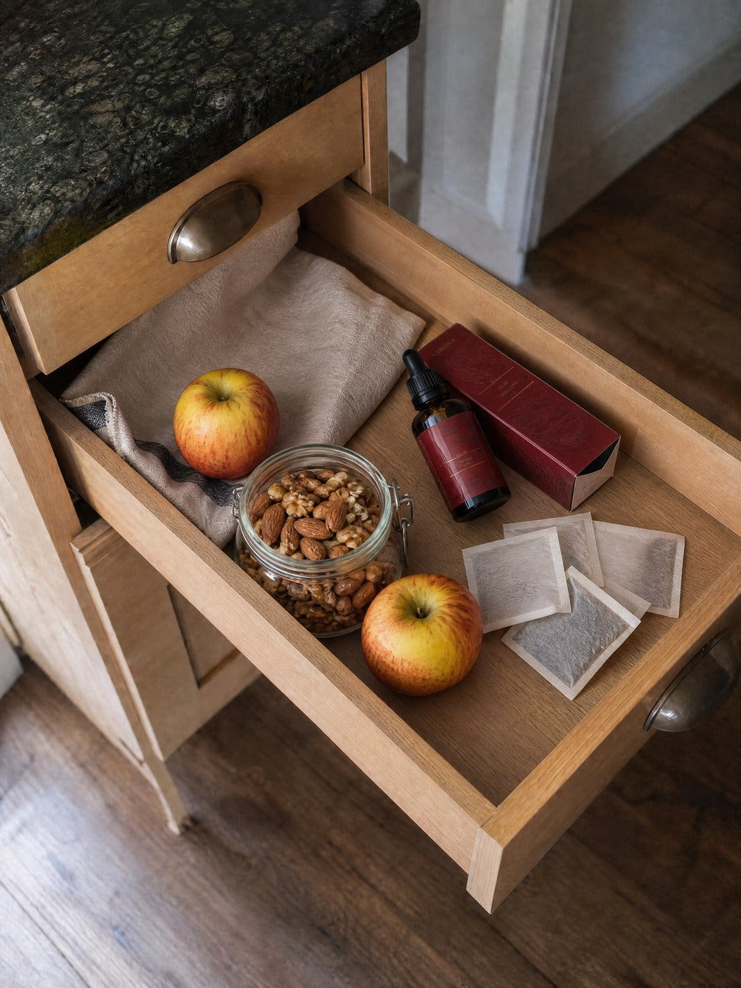 El mismo cajón con frutos secos, té, manzanas y el frasco