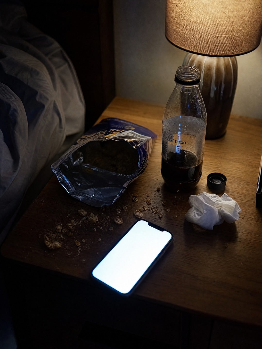 Mesa de noche con paquete vacío, migas y gaseosa