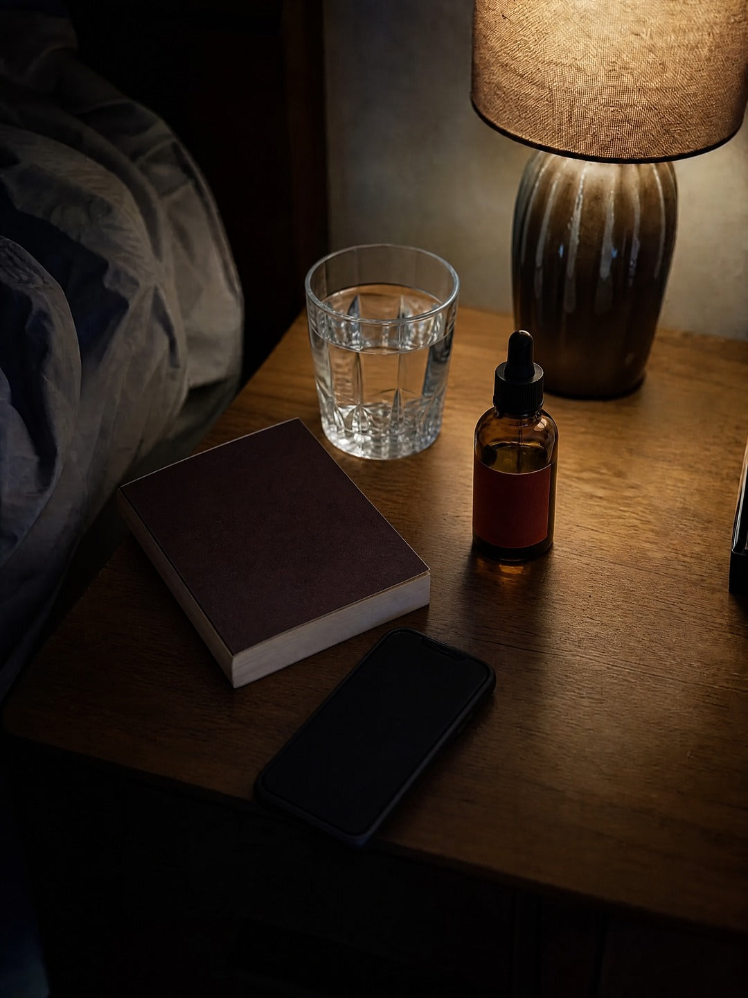 La misma mesa de noche con un vaso de agua, el frasco y un libro